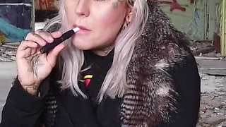 Blonde lady smokes an electronic cigarette on stair