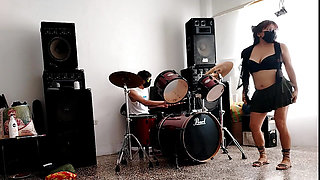 They play the drums for her - she dances, stripping and showing her ass