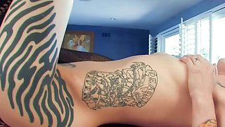 A tattooed gal engages in hardcore onanism while lying on a